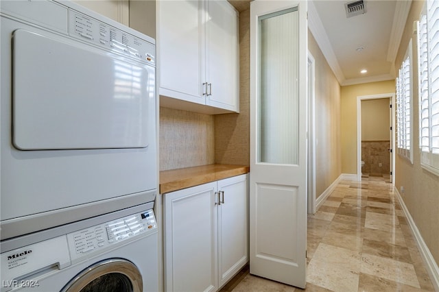 laundry room with stacked washer / drying machine and ornamental molding