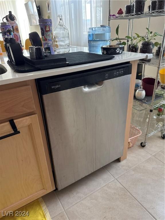 kitchen featuring light tile patterned floors, plenty of natural light, stainless steel dishwasher, and light brown cabinets