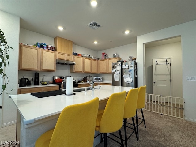 kitchen featuring light carpet, sink, stainless steel refrigerator, and a center island with sink