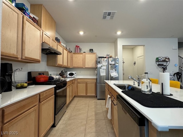 kitchen featuring sink, light tile patterned floors, appliances with stainless steel finishes, a kitchen island with sink, and light brown cabinetry