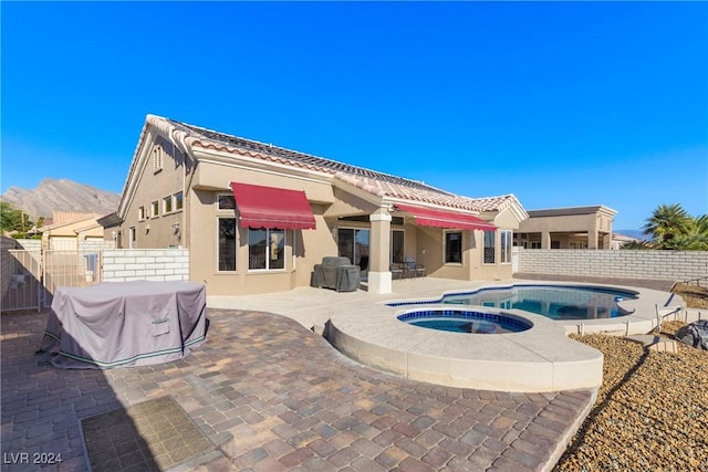 back of house featuring a mountain view, a swimming pool with hot tub, and a patio area