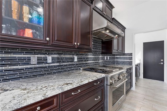 kitchen featuring high end range, backsplash, and light stone countertops