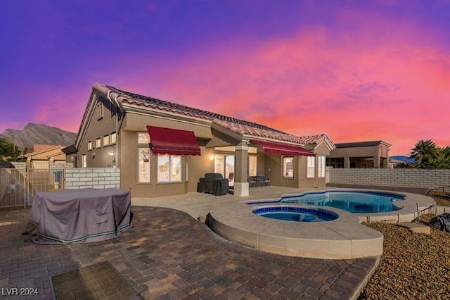 pool at dusk with area for grilling, an in ground hot tub, and a patio