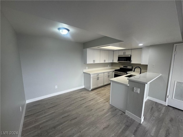 kitchen with white cabinetry, sink, kitchen peninsula, light hardwood / wood-style floors, and appliances with stainless steel finishes