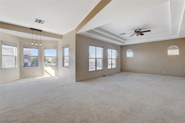 carpeted spare room featuring a tray ceiling and ceiling fan