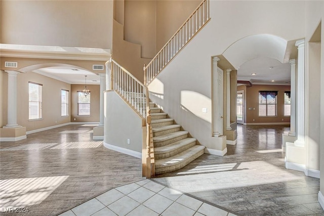 foyer featuring ornamental molding, light wood-type flooring, a wealth of natural light, and a notable chandelier