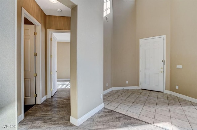 tiled entryway with wood walls and a towering ceiling