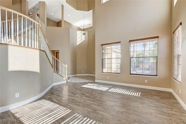 entrance foyer featuring hardwood / wood-style floors, a towering ceiling, and a chandelier