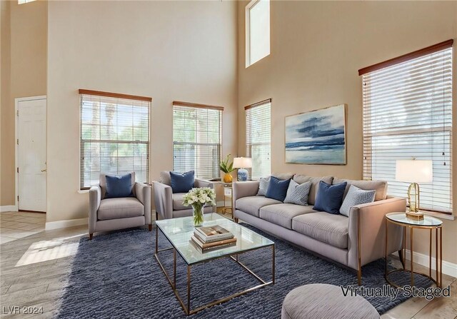 living room featuring plenty of natural light, a high ceiling, and light hardwood / wood-style flooring