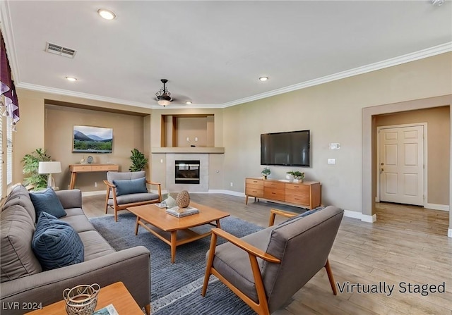 living room featuring crown molding, a fireplace, ceiling fan, and light hardwood / wood-style floors