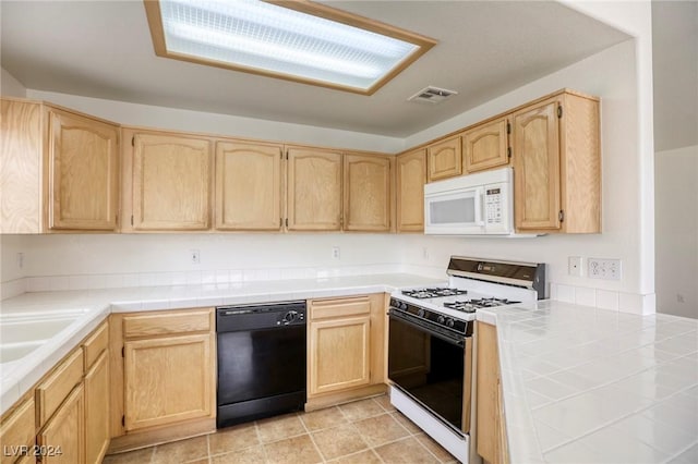 kitchen featuring tile countertops, light brown cabinetry, and white appliances