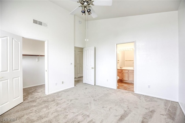 unfurnished bedroom featuring ceiling fan, light colored carpet, a walk in closet, and a closet