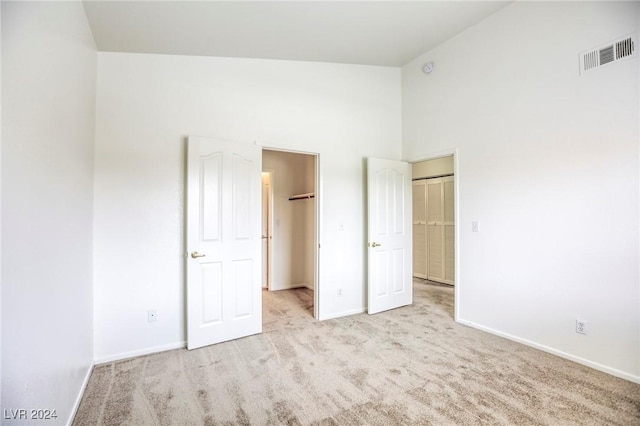 unfurnished bedroom with light colored carpet, high vaulted ceiling, and a closet