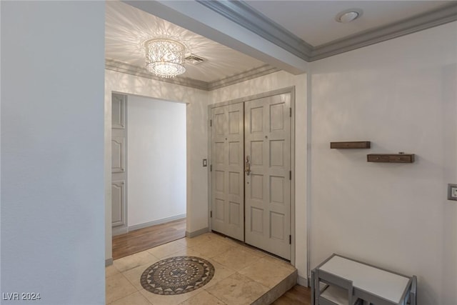 entrance foyer with a notable chandelier, ornamental molding, and light tile patterned floors