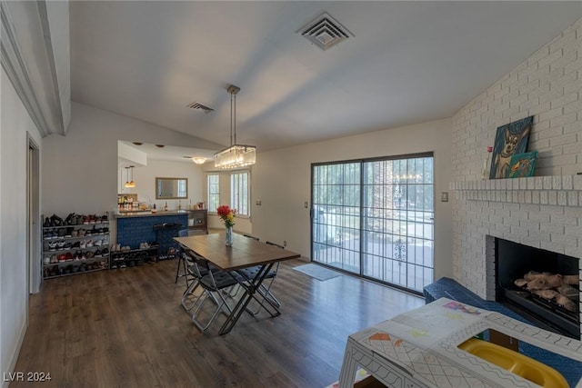 dining area featuring dark wood-type flooring, vaulted ceiling, and a brick fireplace