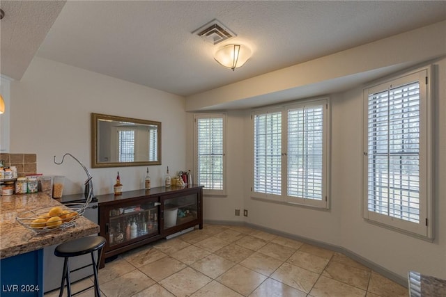 dining area featuring plenty of natural light, light tile patterned flooring, and a textured ceiling