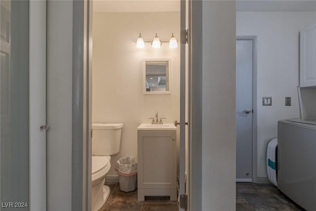 bathroom featuring toilet, washer / dryer, and vanity