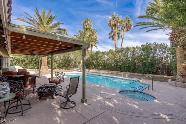 view of swimming pool with an in ground hot tub, a patio, a fire pit, and ceiling fan