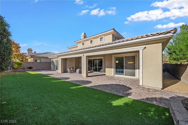 back of property with a yard and a patio