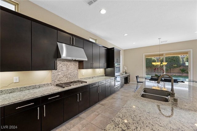 kitchen featuring light stone countertops, sink, a chandelier, decorative light fixtures, and appliances with stainless steel finishes