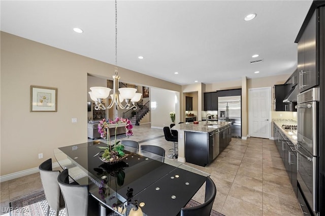 kitchen featuring hanging light fixtures, light stone countertops, an island with sink, stainless steel appliances, and a chandelier