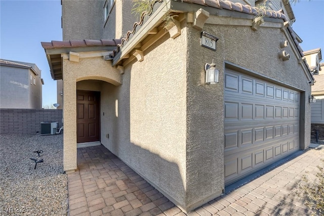 property entrance with cooling unit and a garage