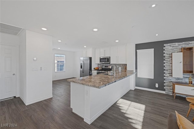 kitchen featuring kitchen peninsula, appliances with stainless steel finishes, tasteful backsplash, stone counters, and white cabinetry