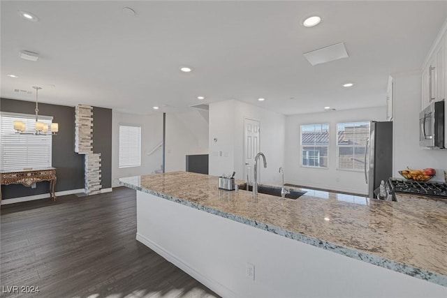 kitchen featuring light stone countertops, stainless steel appliances, sink, white cabinetry, and hanging light fixtures