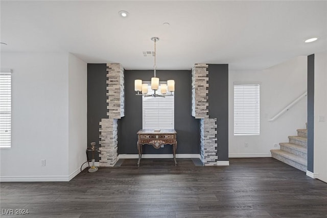 unfurnished dining area with dark hardwood / wood-style floors and an inviting chandelier