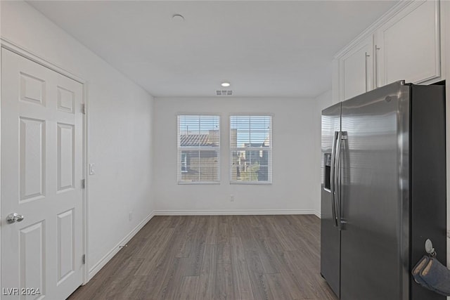 kitchen with stainless steel fridge, white cabinetry, and dark wood-type flooring