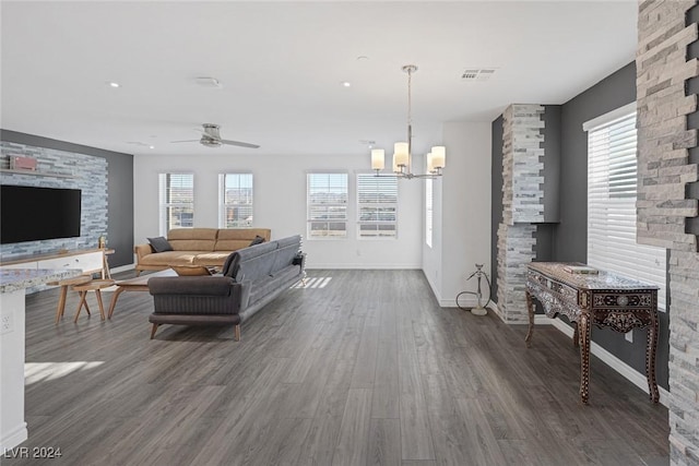 living room with ceiling fan with notable chandelier and dark hardwood / wood-style flooring