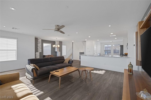 living room featuring dark wood-type flooring and ceiling fan with notable chandelier