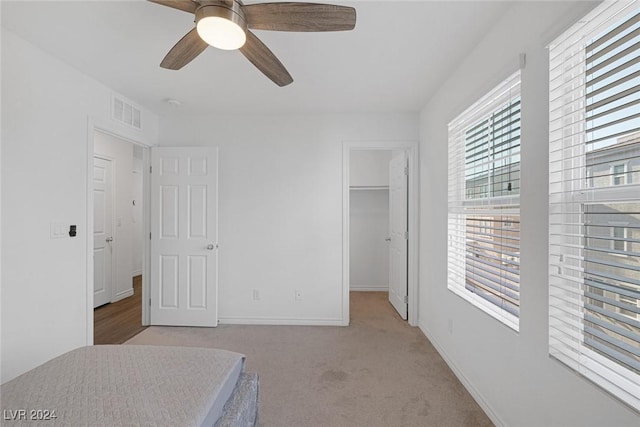 bedroom featuring light carpet, a spacious closet, a closet, and ceiling fan