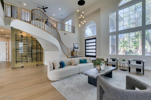 living room featuring ceiling fan, light wood-type flooring, and a towering ceiling