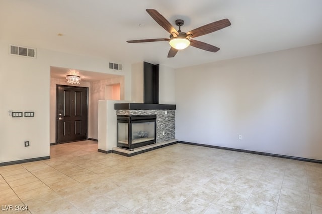 unfurnished living room with ceiling fan, light tile patterned flooring, and a fireplace