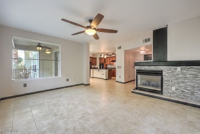 unfurnished living room featuring ceiling fan with notable chandelier, light tile patterned floors, and a tile fireplace