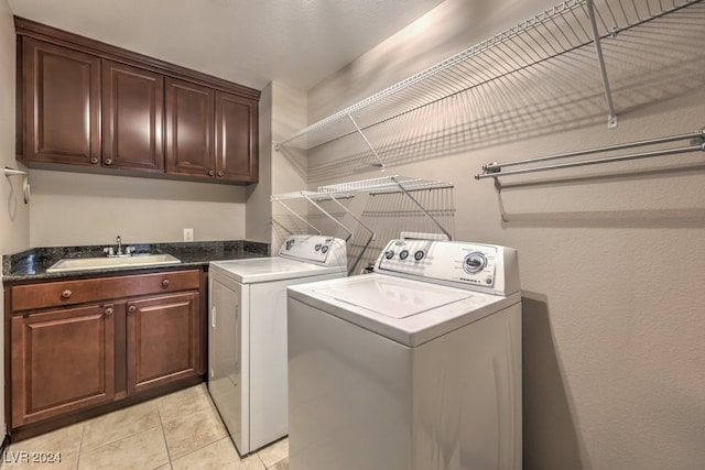 laundry room with cabinets, light tile patterned floors, washer and clothes dryer, and sink