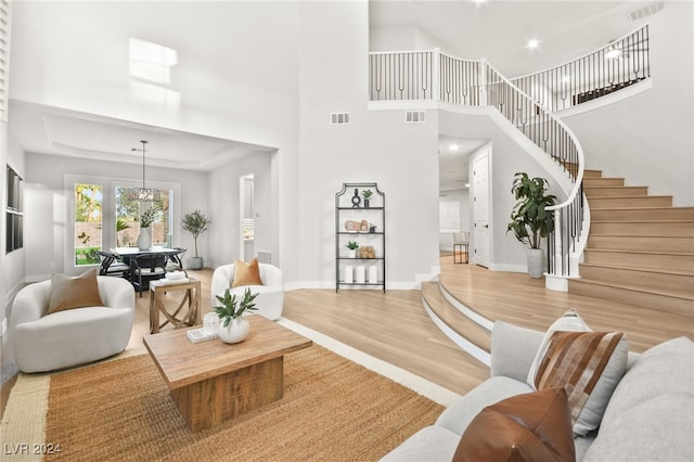 living room with a chandelier, a high ceiling, and light hardwood / wood-style flooring