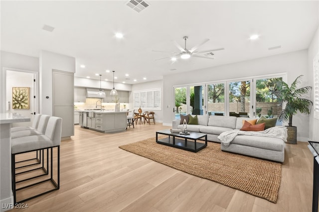 living room with ceiling fan, light hardwood / wood-style flooring, and sink