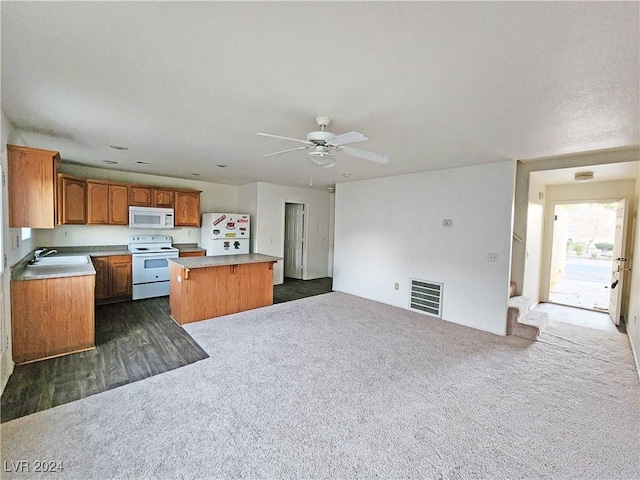 kitchen with dark carpet, white appliances, ceiling fan, sink, and a kitchen island