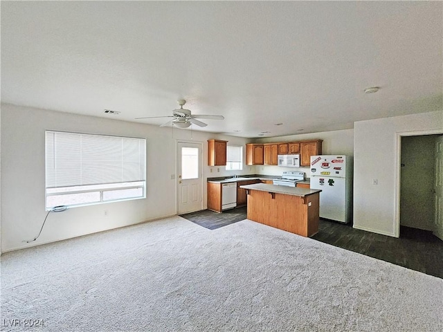 kitchen with dark colored carpet, white appliances, a kitchen island, and ceiling fan