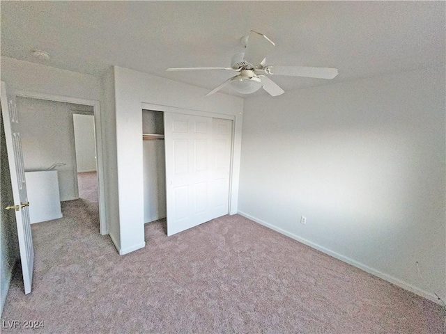 unfurnished bedroom featuring ceiling fan, a closet, and light colored carpet