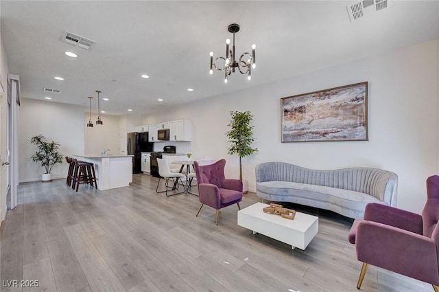 living room featuring an inviting chandelier and light wood-type flooring