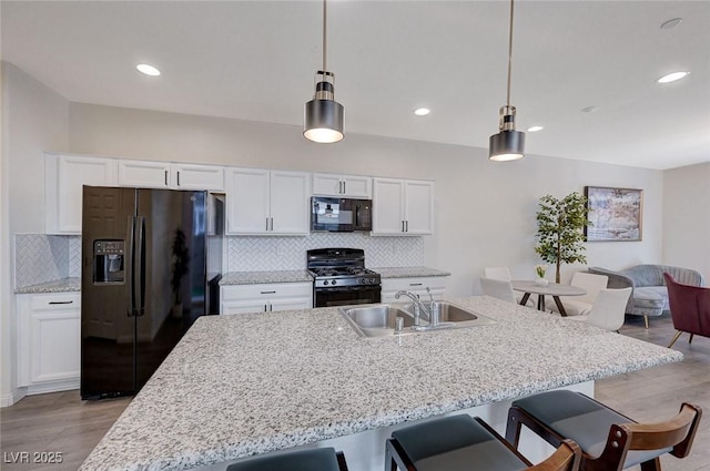 kitchen featuring sink, white cabinetry, tasteful backsplash, pendant lighting, and black appliances