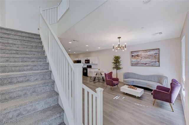 stairs featuring hardwood / wood-style flooring and a notable chandelier