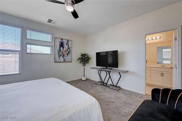 bedroom featuring connected bathroom, light colored carpet, and ceiling fan