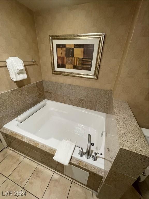 bathroom with tile patterned floors and a relaxing tiled tub