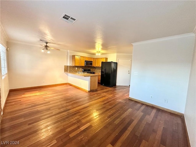 kitchen with a peninsula, visible vents, black refrigerator with ice dispenser, stainless steel microwave, and tasteful backsplash