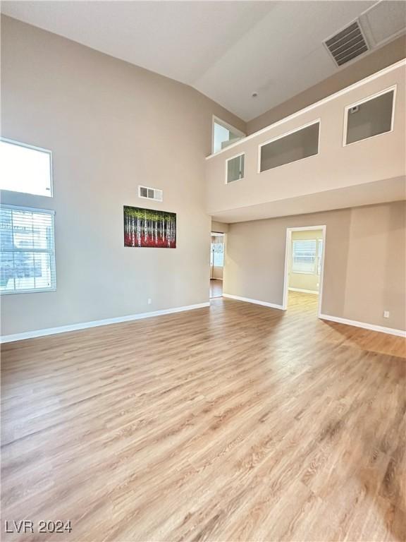 spare room featuring a towering ceiling and light wood-type flooring