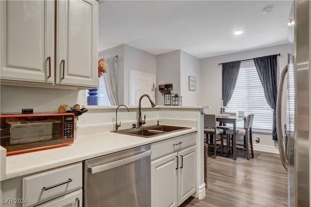 kitchen with a healthy amount of sunlight, sink, stainless steel appliances, and light hardwood / wood-style floors